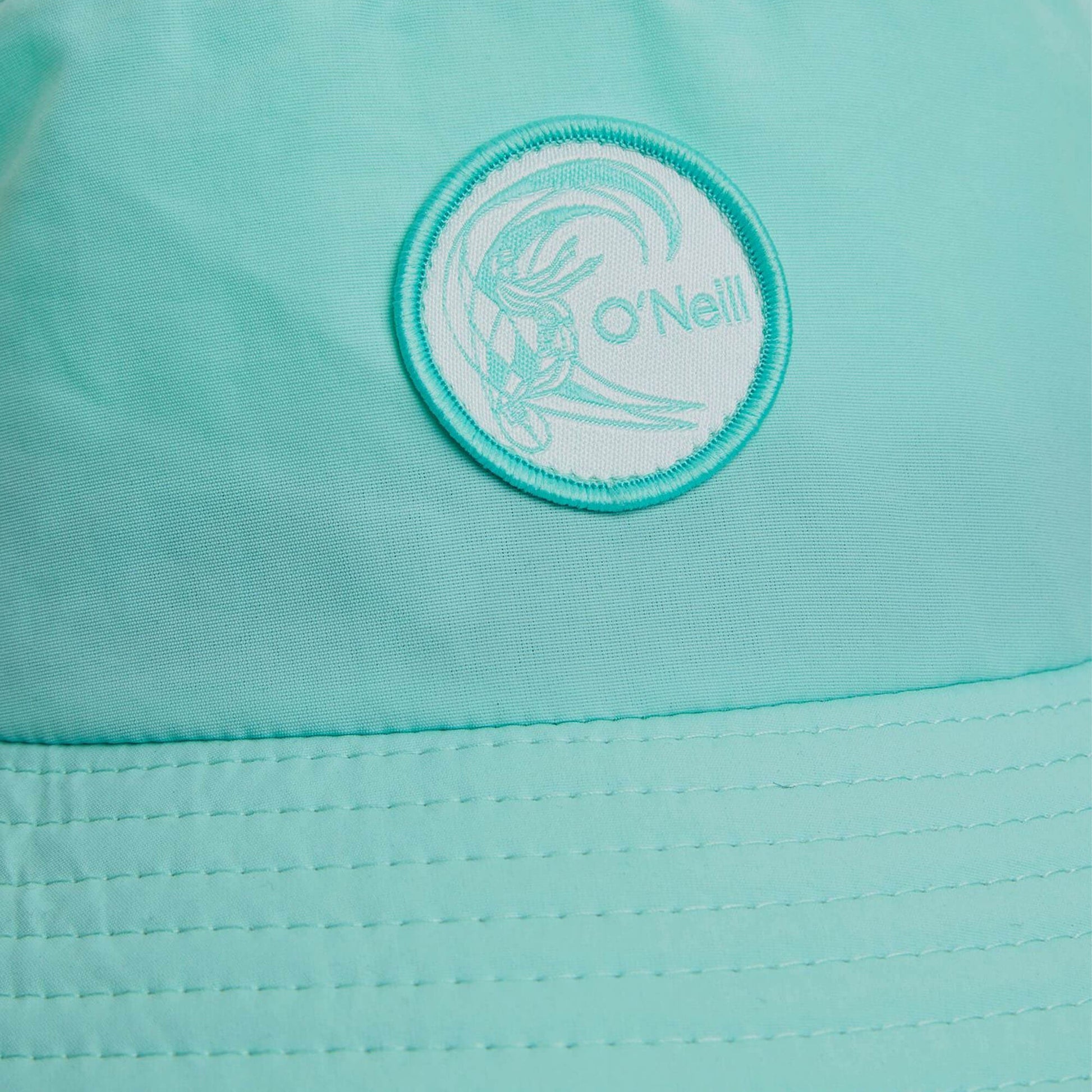 Close-up of a teal jacket with a brand logo on a matching teal background